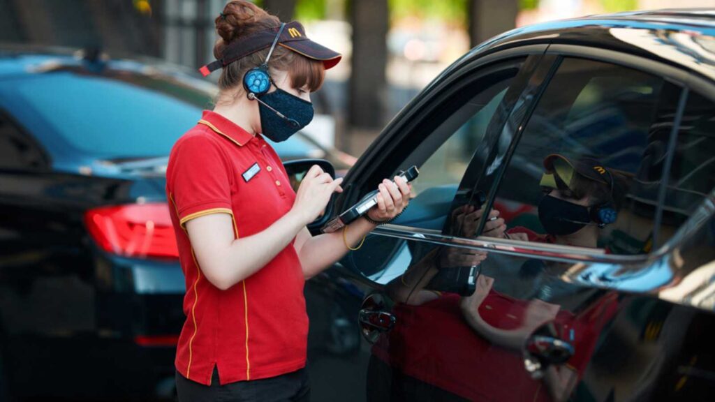 Minsk, Belarus. May 2020. Costumer ordering food from car on McDrive, McDonald`s fast food restaurant. McDonald's employee in protective mask takes orders with tablet at McDrive