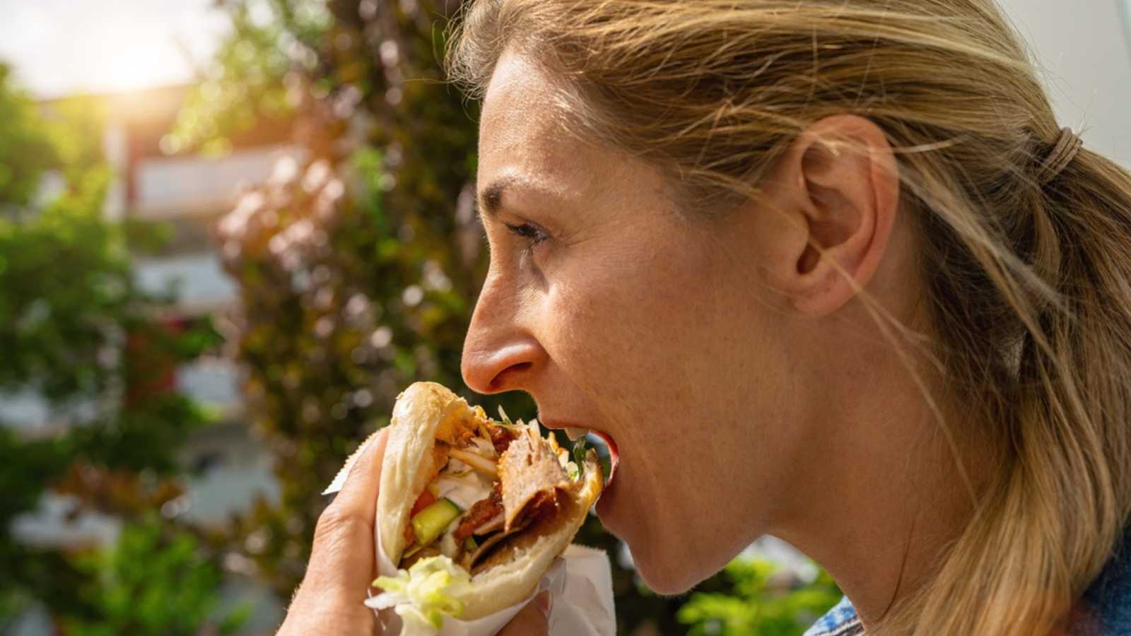 Woman eating a Doner Kebab (sandwich) in Germany famous kebab fast food snack in flatbread.