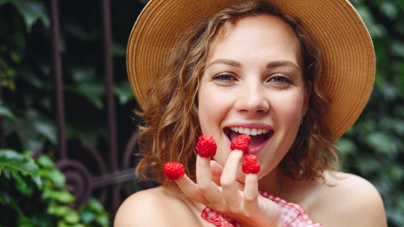 Woman eating raspberry.