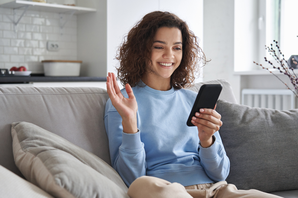 Young Happy Woman Using Phone on Couch