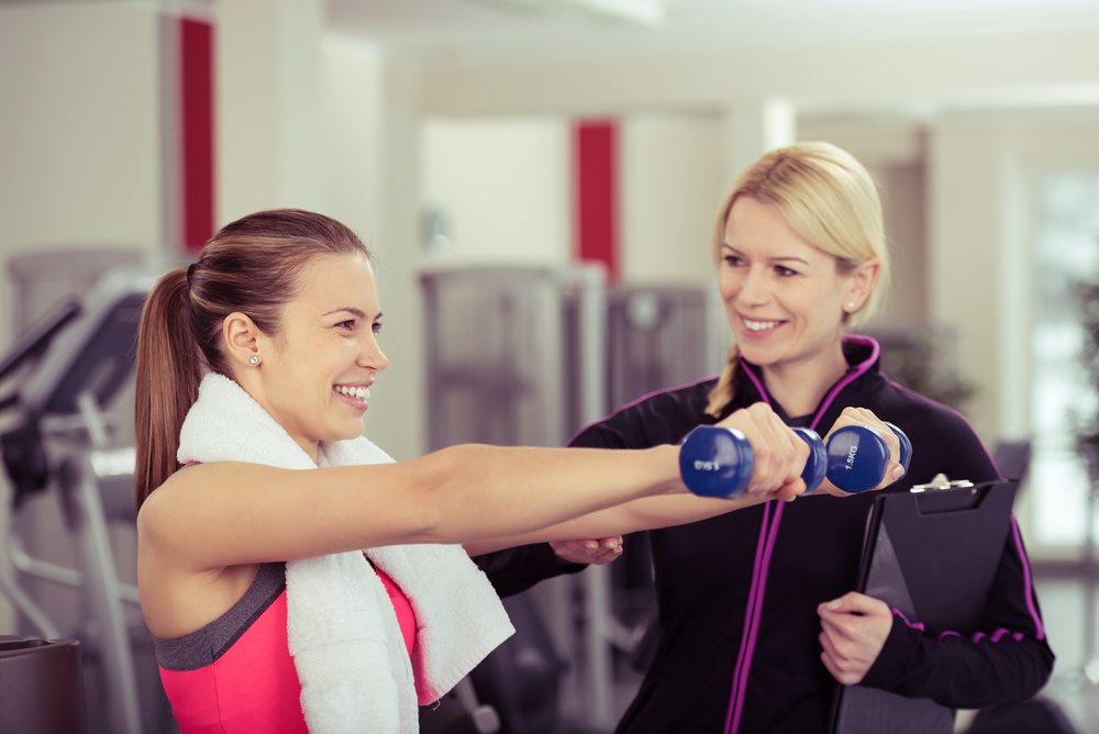 Woman working out at gym with personal trainer