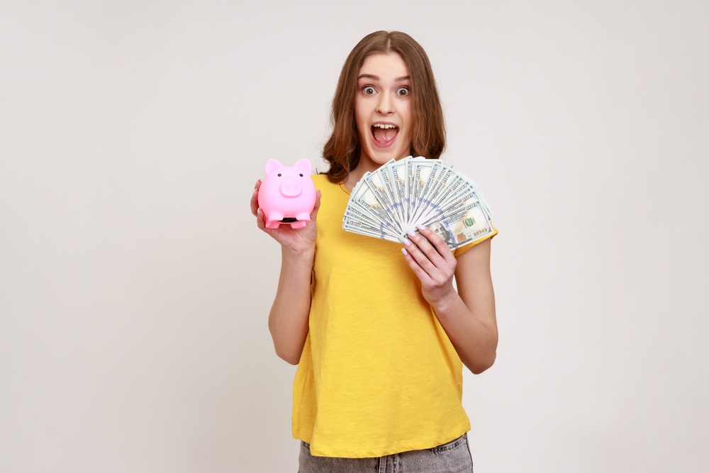 Teenager holding a piggy bank and cash