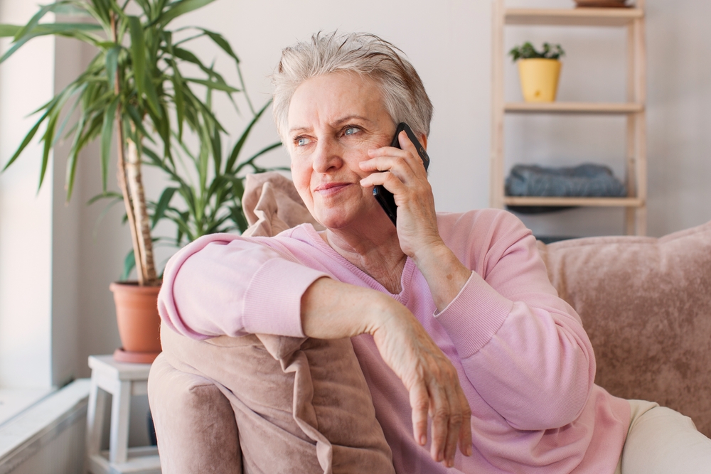 Older woman on couch talking on phone.