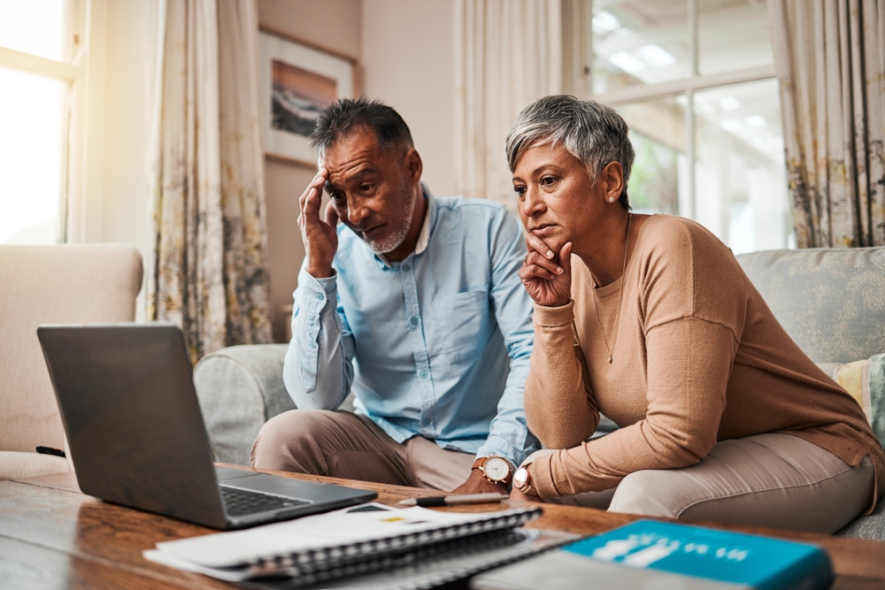 Senior couple worried about finances looking at laptop.